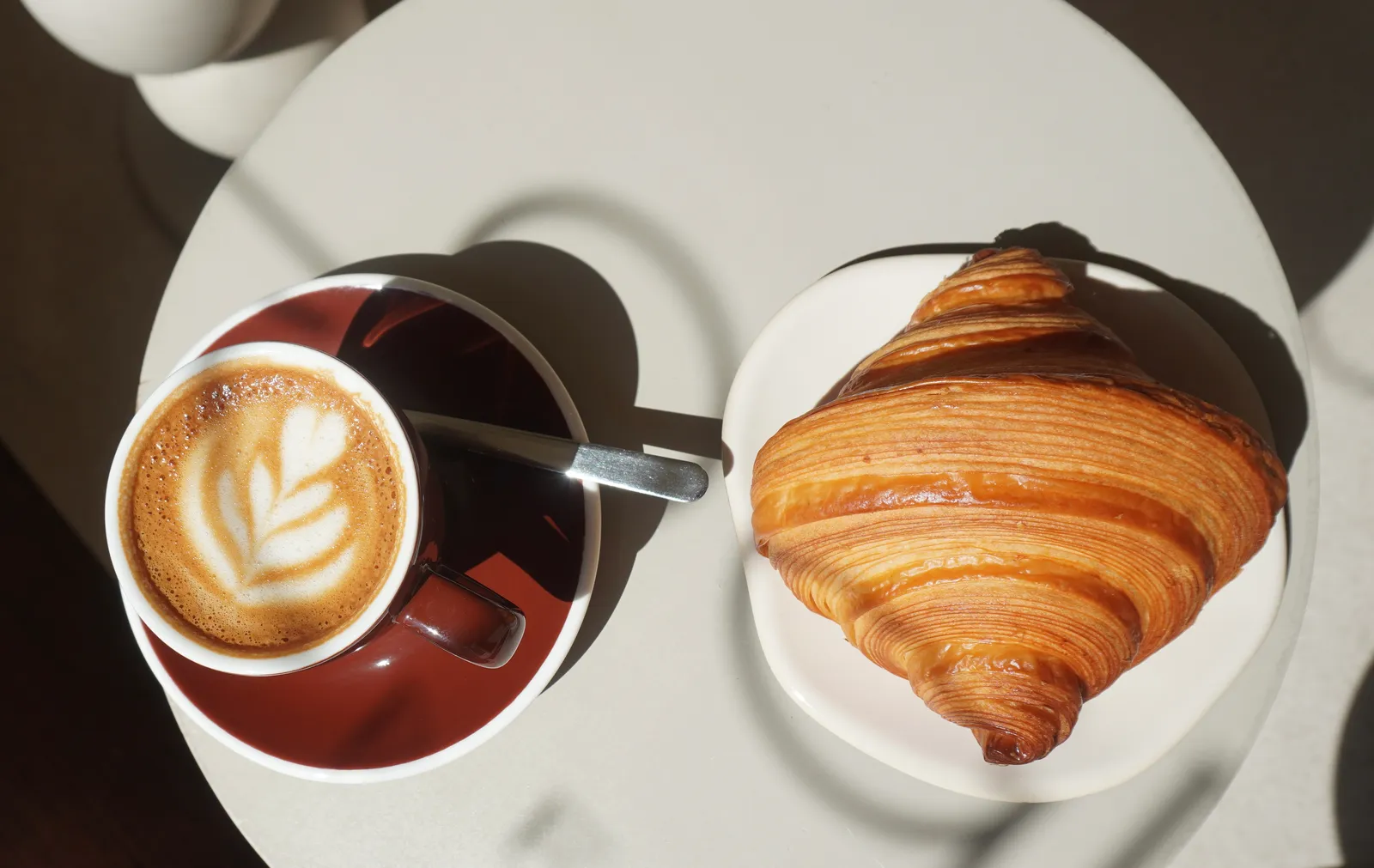 A cappuccino and a cookie on an outdoor café table in the Paris morning.